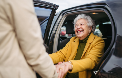 Helping a smiling senior woman out of a car